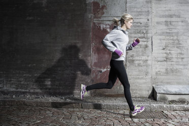 Frau in voller Länge beim Joggen auf der Straße - MASF05649