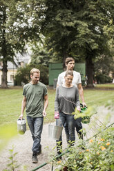 Freunde mit Gartengeräten gehen durch den Garten - MASF05675