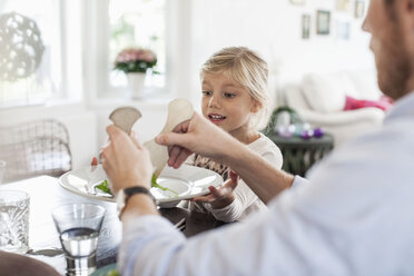 Father serving salad to daughter at dining table - MASF05680