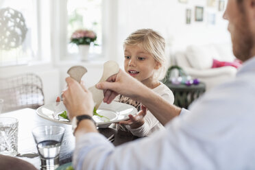 Vater serviert seiner Tochter am Esstisch Salat - MASF05680