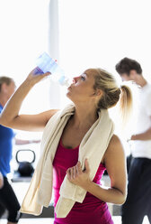 Fitte junge Frau trinkt Wasser im Fitnessstudio - MASF05681