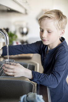 Junge füllt Wasser in ein Glas aus dem Wasserhahn in der Küche - MASF05700