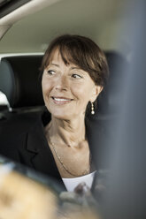 Businesswoman smiling while looking out through taxi window - MASF05709