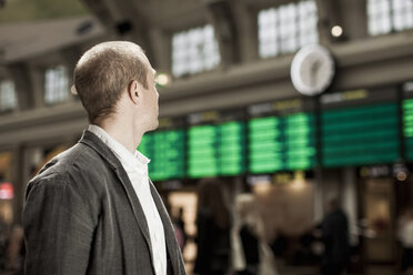 Geschäftsmann mit Blick auf die Ankunft-Abfahrtstafel auf dem Bahnhof - MASF05712