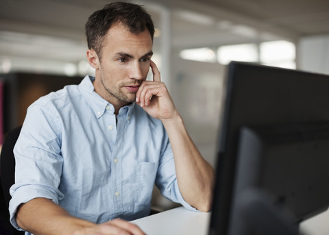 Geschäftsmann mit Desktop-PC am Schreibtisch im Büro, lizenzfreies Stockfoto