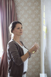 Businesswoman looking at memo notes on whiteboard - MASF05752