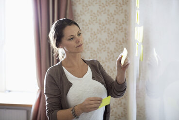 Businesswoman sticking memo notes on whiteboard - MASF05753