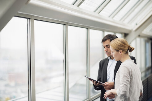 Business people using digital tablet at window in office - MASF05798