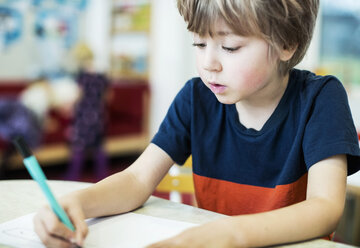 Boy drawing on paper at table in kindergarten - MASF05804