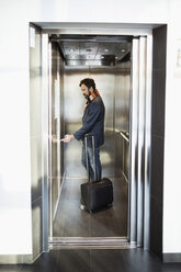 Geschäftsmann drückt den Knopf im Aufzug eines Hotels - MASF05814