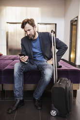 Businessman using mobile phone at hotel lobby - MASF05819