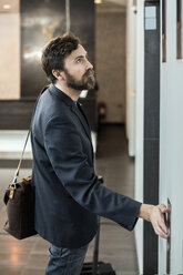 Geschäftsmann drückt den Knopf des Aufzugs im Hotel - MASF05822