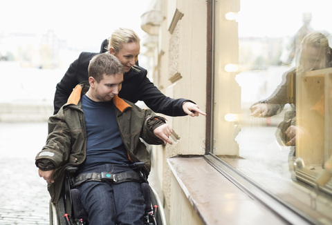 Disabled man on wheelchair widow shopping with caretaker stock photo