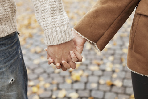 Paar hält sich im Herbst an den Händen, lizenzfreies Stockfoto