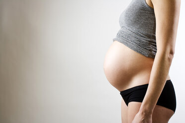 Seitenansicht einer schwangeren Frau auf grauem Hintergrund - MASF05940