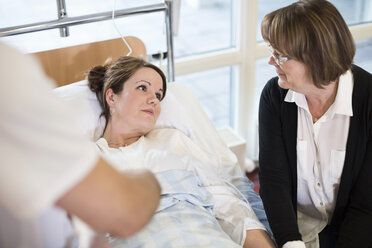 Ältere Frau betrachtet ihre Tochter, die auf dem Bett im Krankenhaus liegt - MASF05987