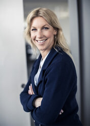 Side view portrait of happy businesswoman standing arms crossed in office - MASF05989