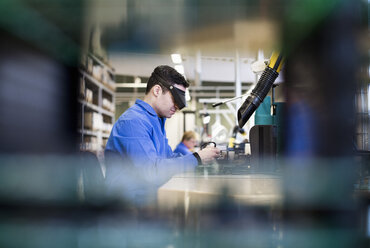 Seitenansicht eines männlichen Technikers mit Schutzbrille bei der Arbeit in der Industrie - MASF05994