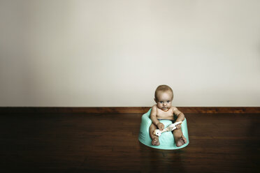 Baby Mädchen mit Spielzeug sitzt auf Töpfchen gegen Wand zu Hause - CAVF43475