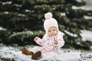 Kleines Mädchen auf einer Decke sitzend bei Schneefall - CAVF43484