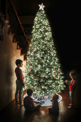 Geschwister am Weihnachtsbaum zu Hause, lizenzfreies Stockfoto