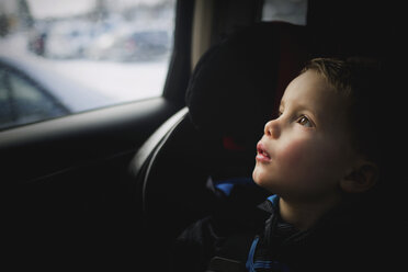 Nachdenklicher Junge, der während der Fahrt im Auto nach oben schaut - CAVF43516