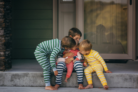 Verliebte Brüder küssen ihre Schwester vor dem Haus, lizenzfreies Stockfoto