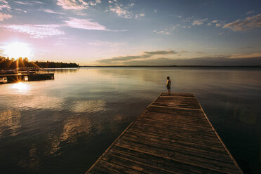 High angle view of shirtless boy standing on jetty against sky during sunset - CAVF43524