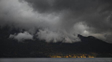 Blick von oben auf Gewitterwolken über einem Berg am See in der Abenddämmerung - CAVF43572