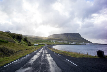 Landschaftliche Ansicht der leeren Straße am Meer gegen bewölkten Himmel - CAVF43591