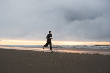 Mann joggt am Strand gegen bewölkten Himmel - CAVF43609