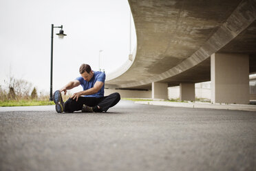 Determined man exercising while sitting on street - CAVF43612