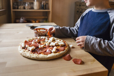 Mittelteil eines Jungen bei der Zubereitung einer Pizza zu Hause - CAVF43629
