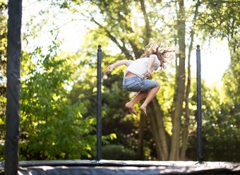 Full length of girl jumping on trampoline at park - CAVF43647