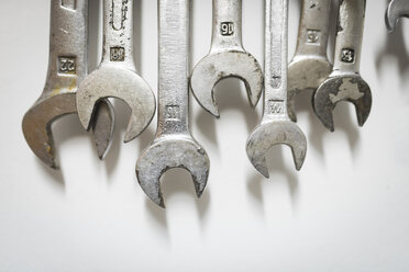 Close-up of wrenches hanging on white wall at workshop - CAVF43755