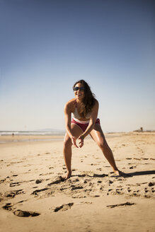 Volle Länge der glücklichen Frau spielt Volleyball am Strand - CAVF43784