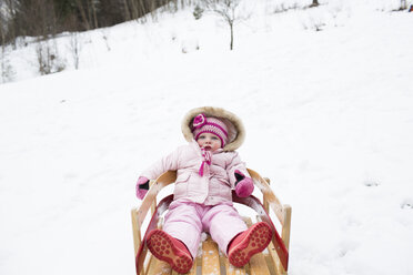 Portrait of cute girl in warm clothing sitting on sled - CAVF43786