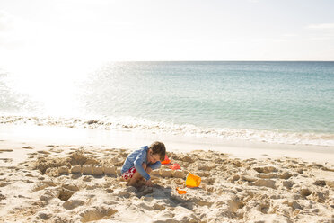 Junge baut Sandburg am Strand gegen den Himmel an einem sonnigen Tag - CAVF43793