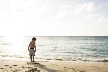 Rückansicht eines am Strand stehenden Jungen ohne Hemd gegen den Himmel an einem sonnigen Tag - CAVF43796