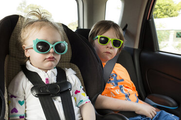 Siblings in sunglasses traveling in car - CAVF43808