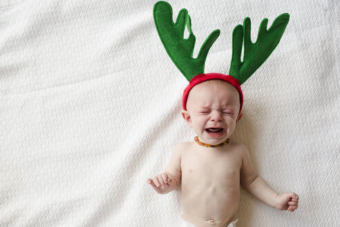 Hohe Winkel Ansicht der niedlichen Baby-Junge in Rentier Hörner weinen, während auf dem Bett liegend - CAVF43817