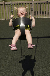 Hohe Winkel Ansicht der niedlichen Mädchen schwingen auf dem Spielplatz während des sonnigen Tages - CAVF43835