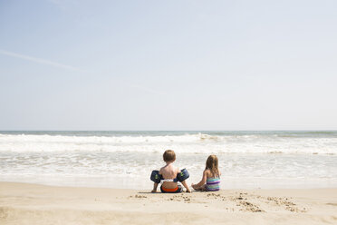 Rückansicht von Geschwistern, die sich am Strand gegen den Himmel an einem sonnigen Tag vergnügen - CAVF43841
