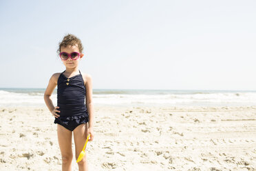 Porträt eines Mädchens in Badekleidung mit Sonnenbrille am Strand an einem sonnigen Tag - CAVF43843