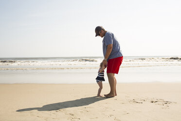 Vater und Tochter genießen am Strand gegen den Himmel an einem sonnigen Tag - CAVF43847