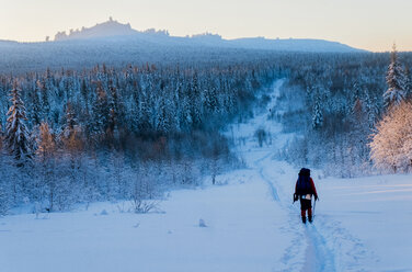 Rear view of man skiing on snowy field against sky - CAVF43855