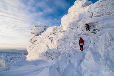 Freunde wandern auf schneebedecktem Berg gegen den Himmel - CAVF43858