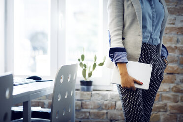 Midsection of businesswoman holding tablet computer in office - CAVF43890