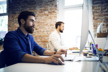 Young businessmen using computer at desk in creative office - CAVF43923