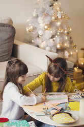 Geschwister zeichnen Weihnachtsbaum auf Papier zu Hause - CAVF43946